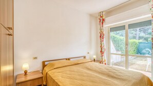 A bedroom with a bed, bedside tables, a window with curtains, and a view of greenery outside. - 1 bedroom cozy apartment in Orbetello (Orbetello)