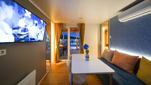 Een modern interieur met een televisie aan de muur, een tafel en een bank.