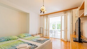 Un dormitorio con cama, escritorio, televisor y vistas al exterior.