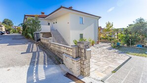 Una casa de dos pisos con un muro de piedra, una escalera y un camino de entrada pavimentado.