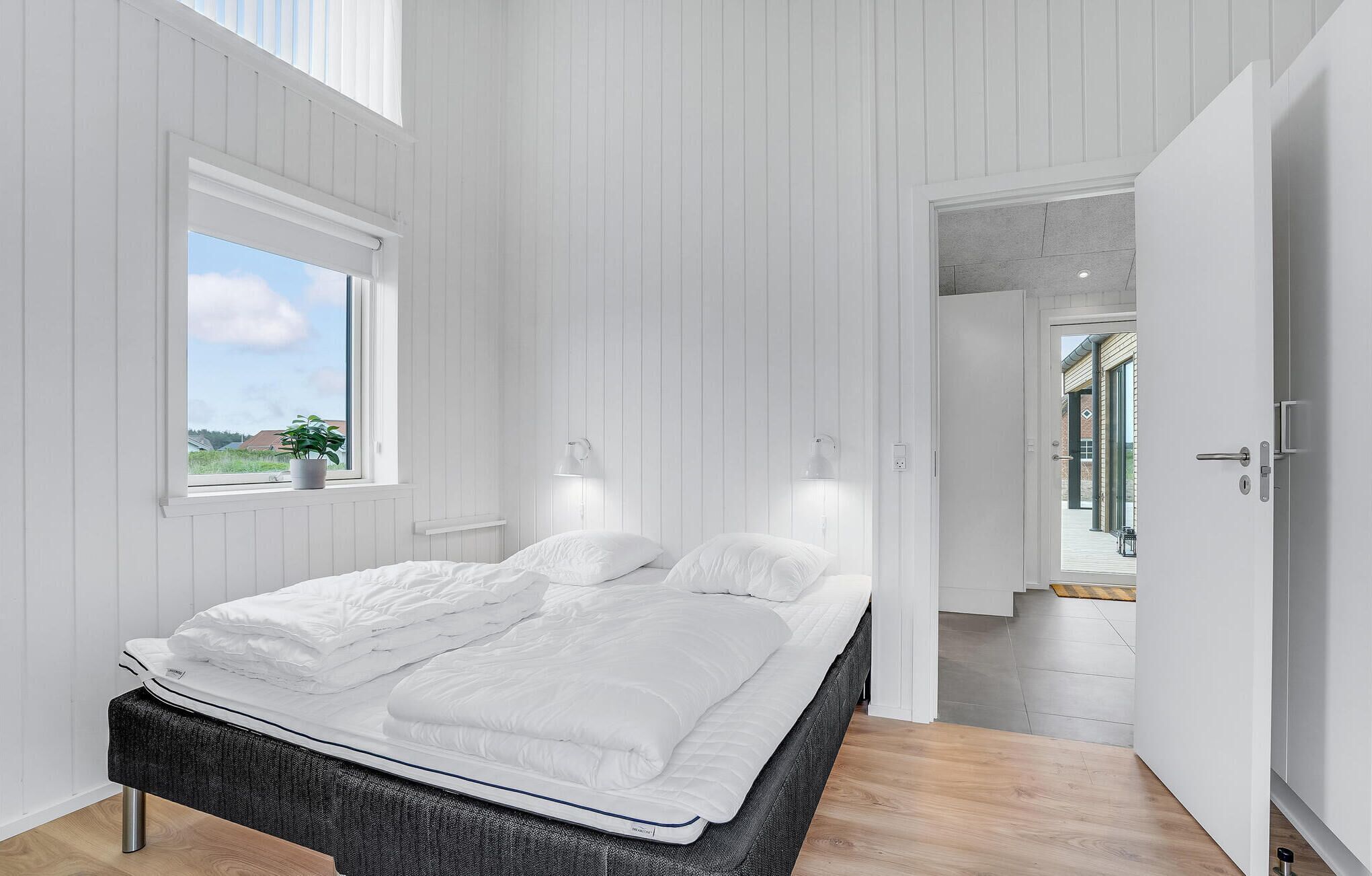 Un dormitorio moderno con una cama grande, una ventana con vistas y una puerta que da a una escalera.