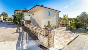 Una casa de dos pisos con un muro de piedra, una escalera y un camino de entrada pavimentado.