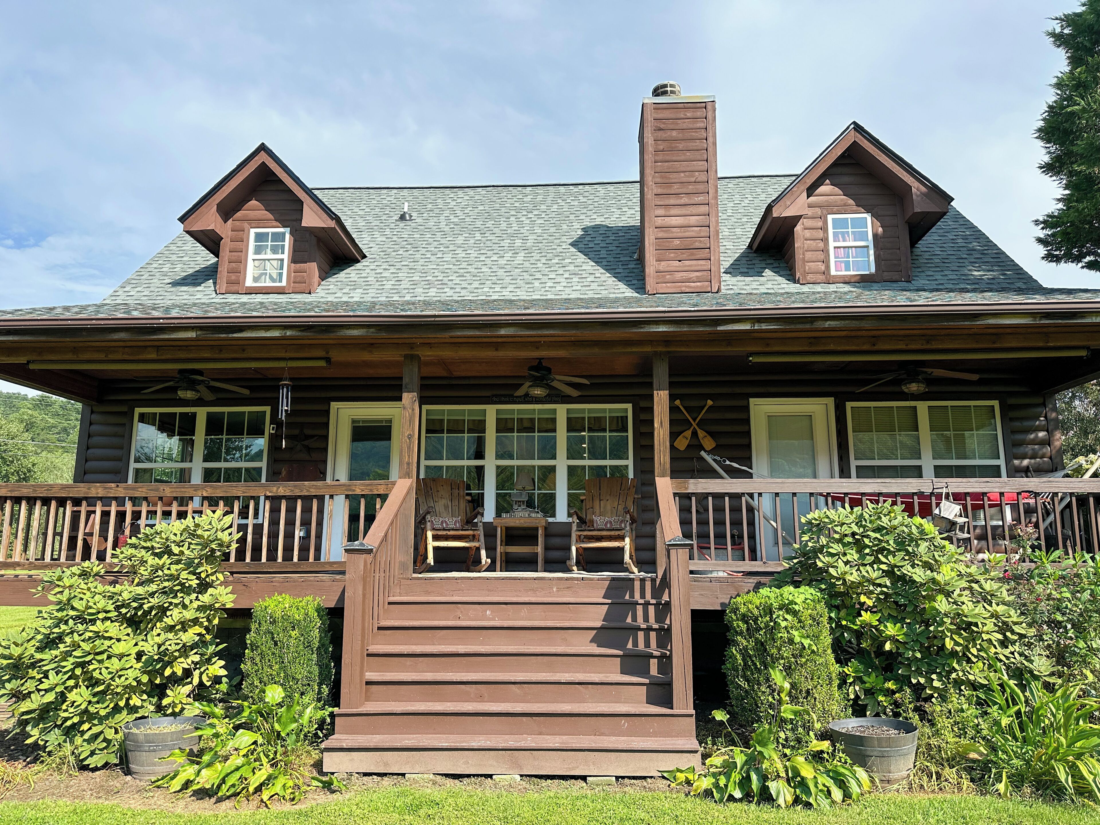 A log cabin with a porch, a chimney, and a set of stairs leading to the entrance.