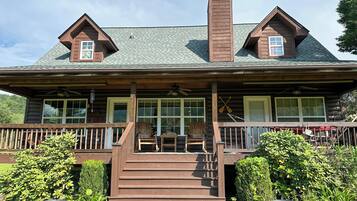 A log cabin with a porch, a chimney, and a set of stairs leading to the entrance.