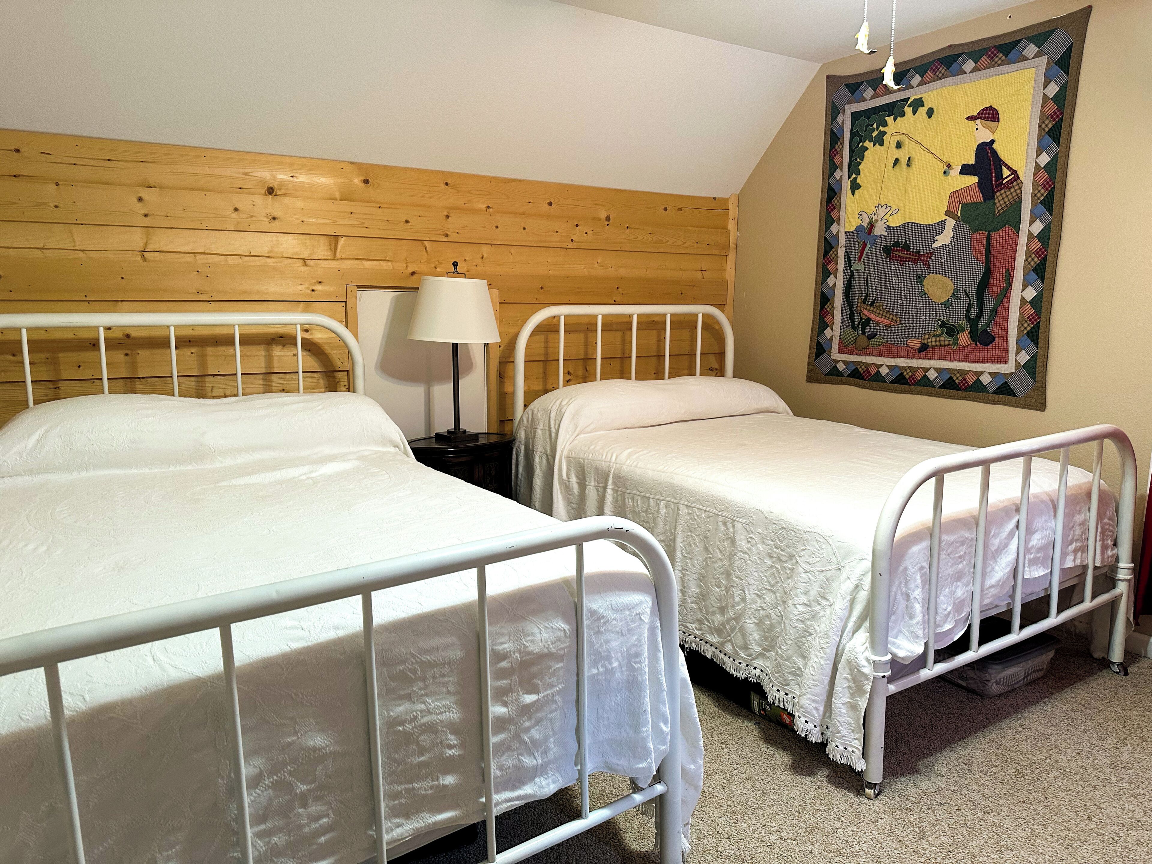 Ein Zimmer mit Holzwandverkleidung und zwei Betten mit Metallgestellen.