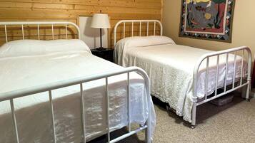 Ein Zimmer mit Holzwandverkleidung und zwei Betten mit Metallgestellen.