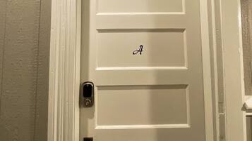 Uma porta branca com uma pequena janela no topo e a letra 'A' na porta.