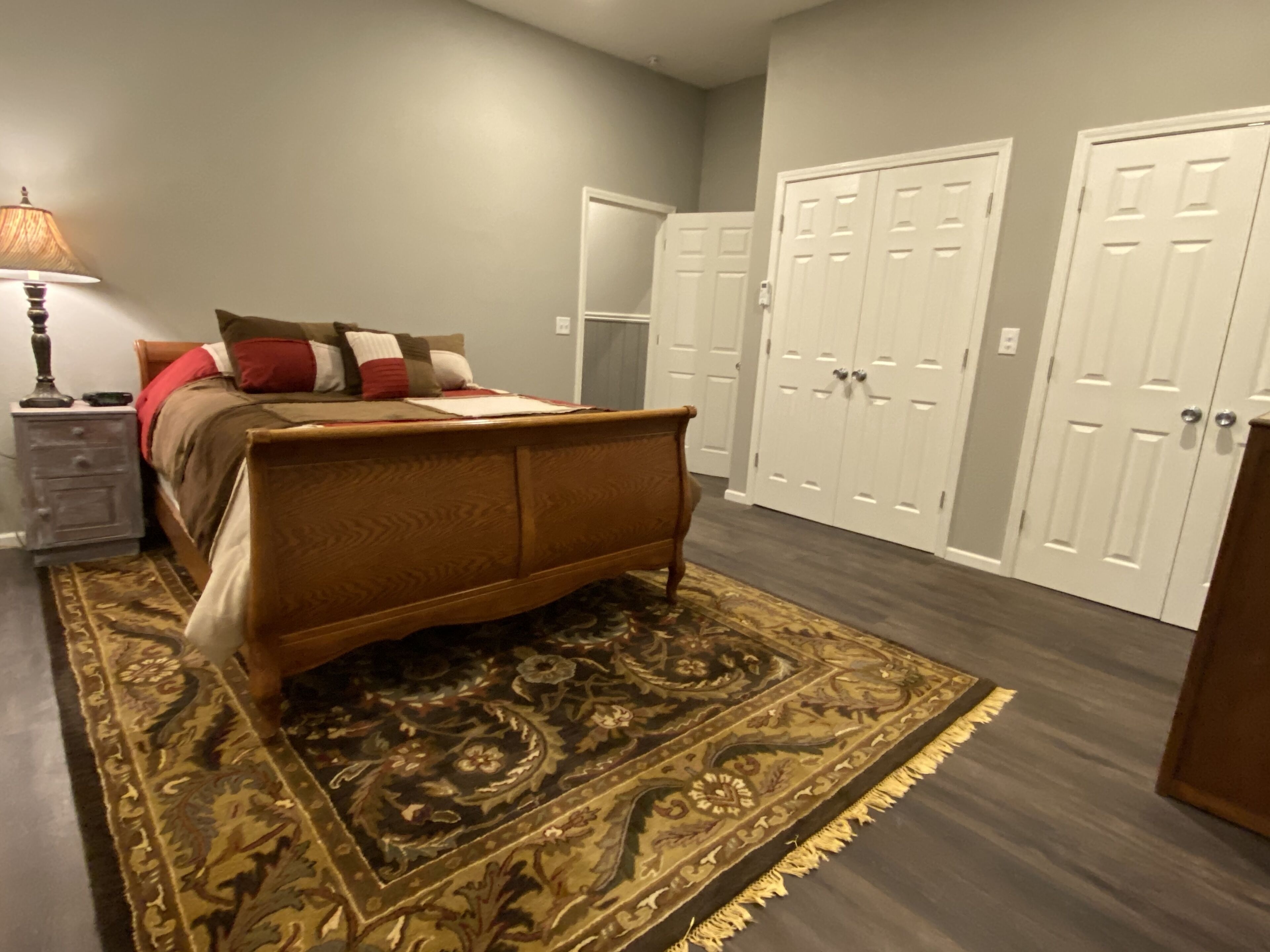 A bedroom with a bed, nightstand, lamp, and two wardrobes.