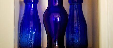 A shelf with three blue glass vases of varying shapes.