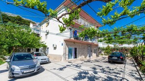 A residential street with parked cars, a white building with a red roof, and a balcony with clothes hanging. - Gorgeous apartment in Duce with WiFi (Duce)