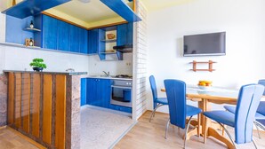 A modern kitchen with blue cabinets, a wooden island, and a dining area with blue chairs. - Gorgeous apartment in Duce with WiFi (Duce)