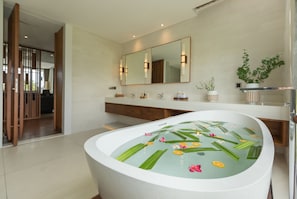Une salle de bain moderne avec une baignoire sur pieds, un grand miroir et un meuble-lavabo en bois.