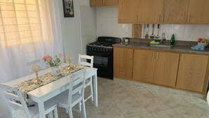 Een keuken met witte kastjes, een fornuis en een eettafel met stoelen.