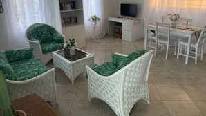 Een woonkamer met groene gestreept meubilair, een wit bureau en een televisie.