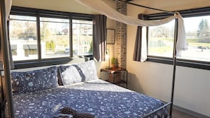 Een bed met hemelbed, een bakstenen muur en een raam met gordijnen.