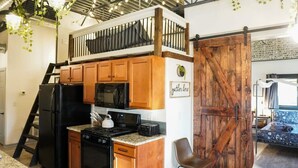 Une cuisine de taille réduite, avec des meubles en bois, un réfrigérateur noir, un four à micro-ondes et une cuisinière.