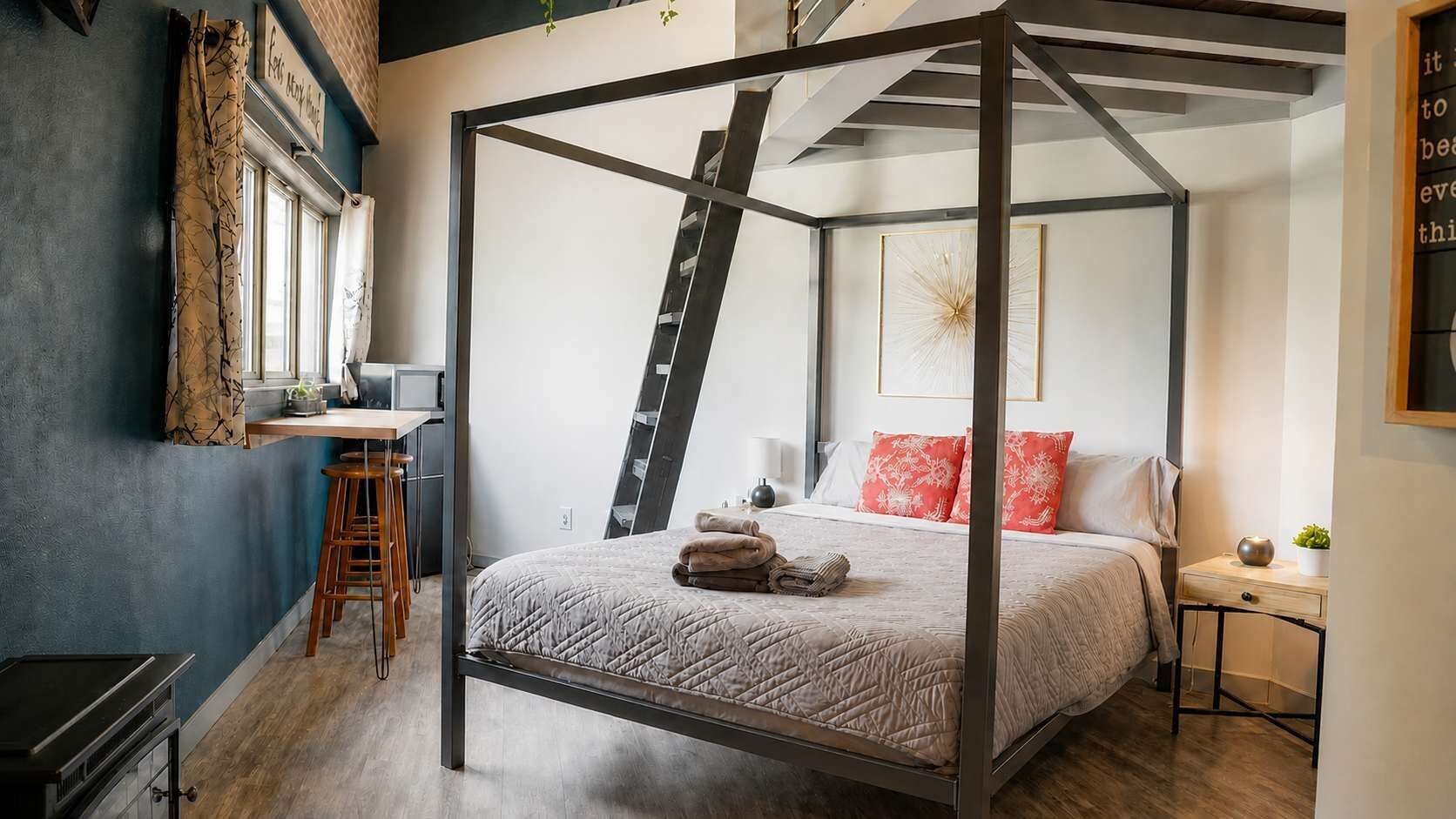 Ein Schlafzimmer mit einem Himmelbett, einem Schreibtisch mit Stuhl und einer an der Wand stehenden Leiter.