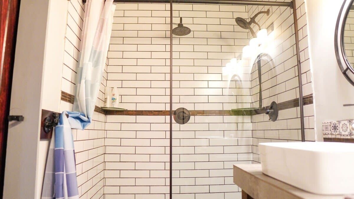 Une salle de bain avec une douche, un lavabo et un miroir.