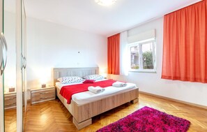 A bedroom with a wooden bed, white bedding, a red blanket, and a pink rug. - Stunning apartment in Duce with house sea view (Duce)