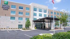 A Holiday Inn Express & Suites building with a stone facade, multiple windows, and an American flag. - Holiday Inn Express & Suites Tuscaloosa East - Cottondale by IHG (Cottondale)