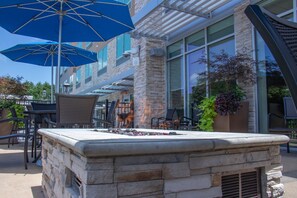An outdoor seating area with stone tables, blue umbrellas, and potted plants. - Holiday Inn Express & Suites Tuscaloosa East - Cottondale by IHG (Cottondale)