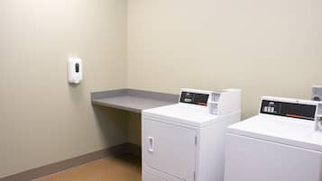 A laundry area with two front-loading washing machines and a wall-mounted soap dispenser.