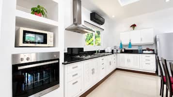A modern kitchen with built-in appliances, white cabinetry, and a window providing natural light.