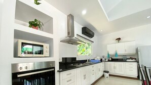 A modern kitchen with white cabinetry, a built-in microwave, a stove, and an oven. - 4 Br Private Pool Villa GA (Chalong)