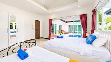 A hotel room with two beds, a balcony with a pool, and a view of the outside.