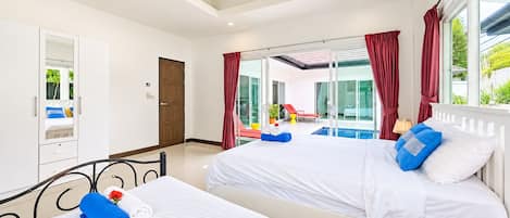 A hotel room with two beds, a balcony with a pool, and a view of the outside.