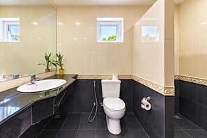 Un baño moderno con lavamanos, inodoro y ducha. Hay dos ventanas que permiten la entrada de luz natural.