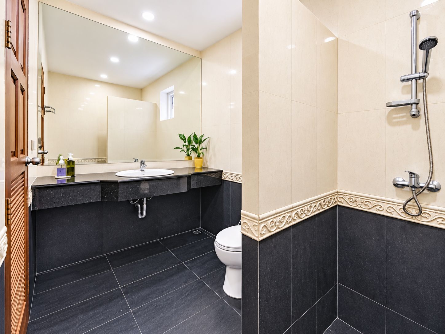 A modern bathroom with a black sink, white toilet, and a shower area.