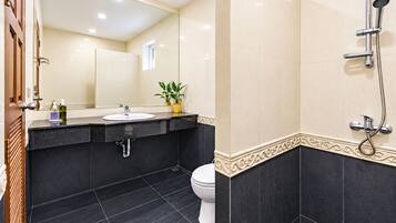 A modern bathroom with a black sink, white toilet, and a shower area.