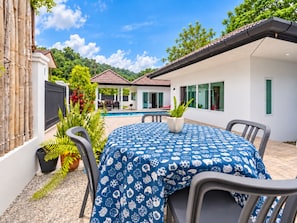Eine Terrasse mit Pool, Gartenmöbeln und einem Tisch mit gemustertem Tischläufer.
