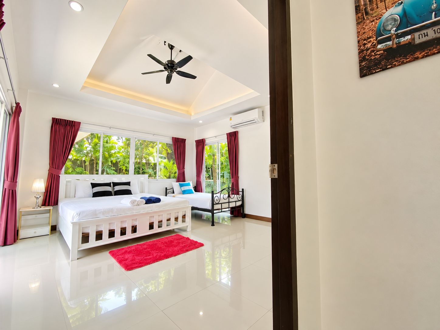 Une chambre d’hôtel équipée d’un lit, d’un bureau, d’une chaise, d’un ventilateur de plafond et d’une fenêtre avec des rideaux.