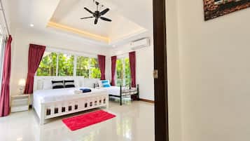 Une chambre d’hôtel équipée d’un lit, d’un bureau, d’une chaise, d’un ventilateur de plafond et d’une fenêtre avec des rideaux.