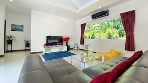 Una sala de estar moderna con un sofá, televisión y una ventana con cortinas.