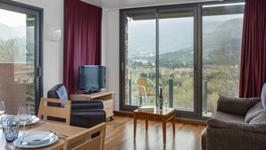 A modern living room with a dining area, large sliding glass doors, a flat-screen TV, and a scenic view.