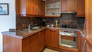 A kitchen with wooden cabinets, granite countertops, stainless steel appliances, and a coffee maker.