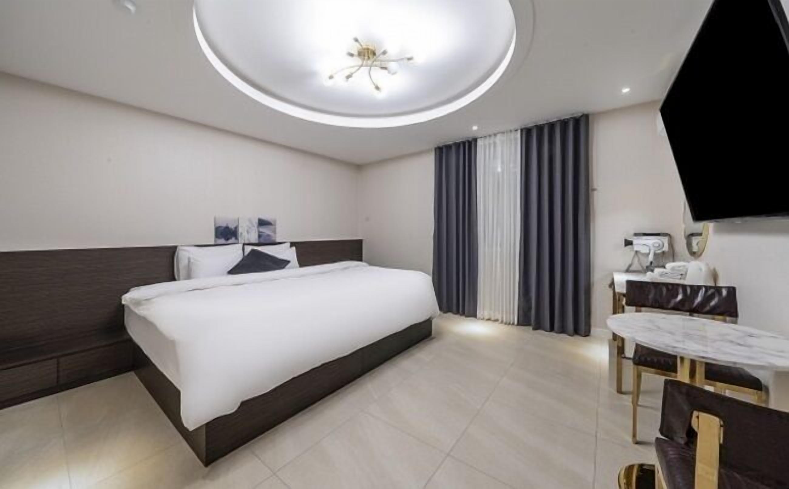 A modern hotel room with a large bed, a desk, and a television.