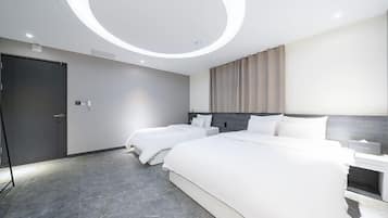 A modern hotel room with a large bed, a smaller bed, a bedside table, a wardrobe, and a circular ceiling light.