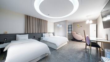 A modern hotel room with two beds, a desk, a chair, a massage chair, and a TV.