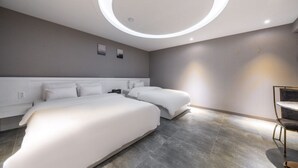 A modern hotel room with two beds, a circular light fixture, and a minimalist design.