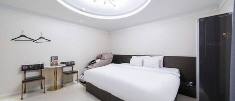 Una habitación de hotel con cama, una lámpara de techo redonda, un armario y una pequeña mesa con sillas.