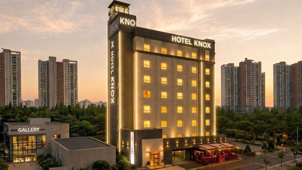 A hotel with a prominent 'HOTEL KNOX' sign, a 'GALLERY' building to the left, and a well-lit entrance.