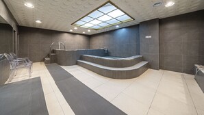 Un área de spa moderna con una bañera grande, asientos cómodos y un tragaluz.