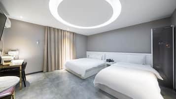 A modern hotel room with two beds, a desk with a chair, and a circular ceiling light.