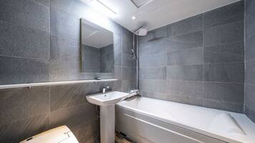 Un bagno moderno con una vasca, un lavandino e uno specchio.