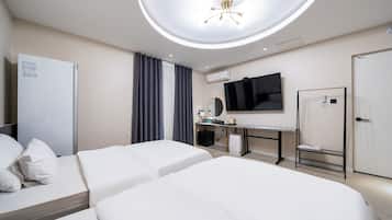 A hotel room with two beds, a desk with a computer, a flat-screen TV, a mirror, and a wardrobe.