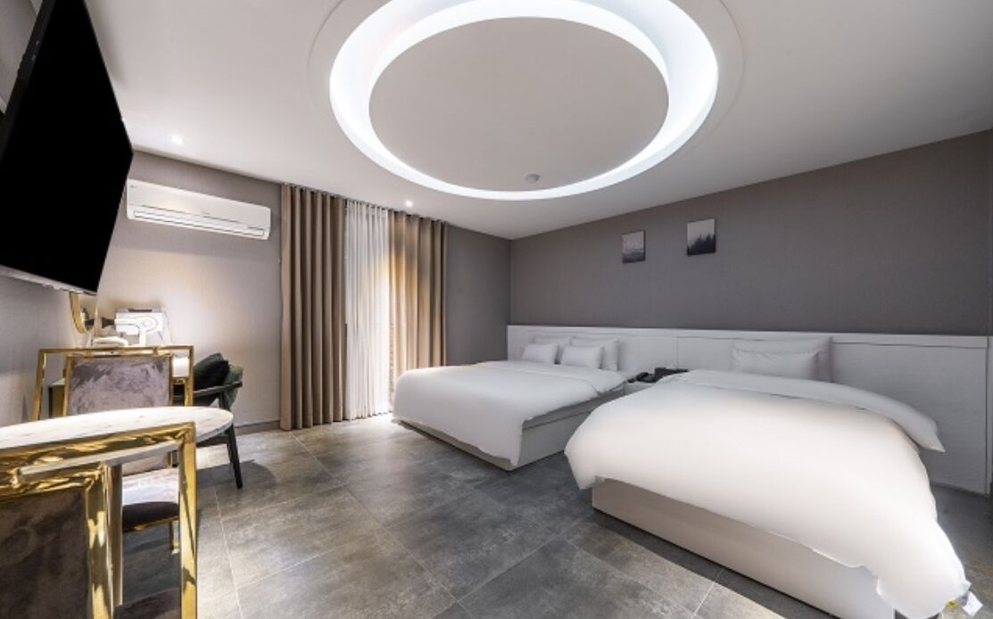 Une chambre d’hôtel moderne avec un grand lit, un bureau avec une chaise et un téléviseur.
